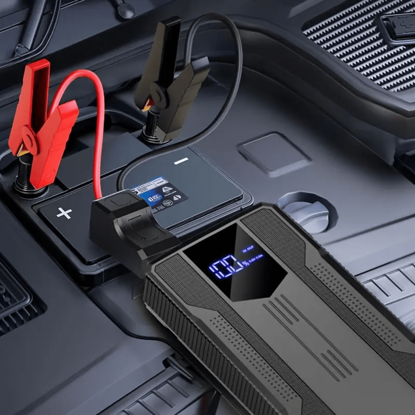 Zwarte PowerVault jumpstarter aangesloten op een autobatterij met rode en zwarte klemmen in motorruimte.
