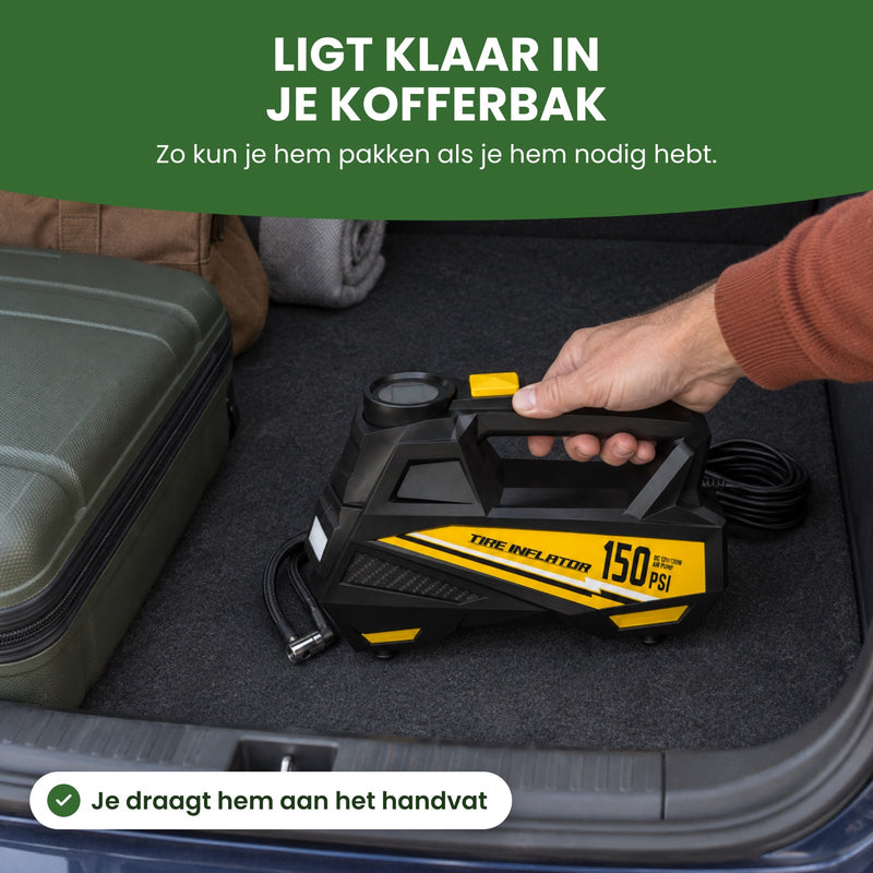 Hand zet de AirBoost aan het handvat in de kofferbak naast een koffer en een weekendtas: hij ligt klaar in je kofferbak