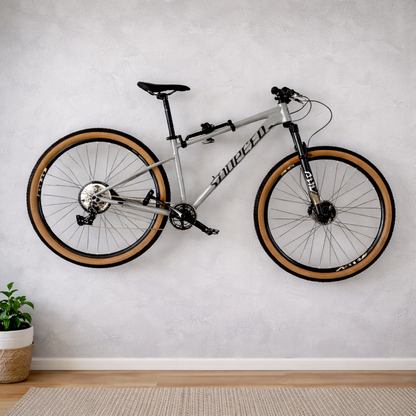Zilverkleurig fiets ophangsysteem aan de muur met een mountainbike horizontaal opgeborgen in een woonkamer.