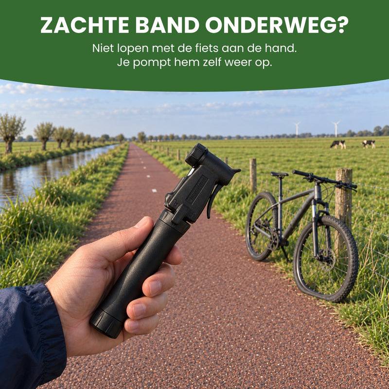 Hand houdt de zwarte mini fietspomp vast op een fietspad in de polder, verderop de fiets met een zachte voorband: je pompt hem zelf weer op