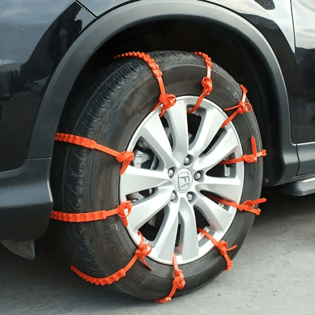 Oranje SnowGrip sneeuwkettingen gemonteerd op autoband, zorgt voor extra grip tijdens winterse omstandigheden.