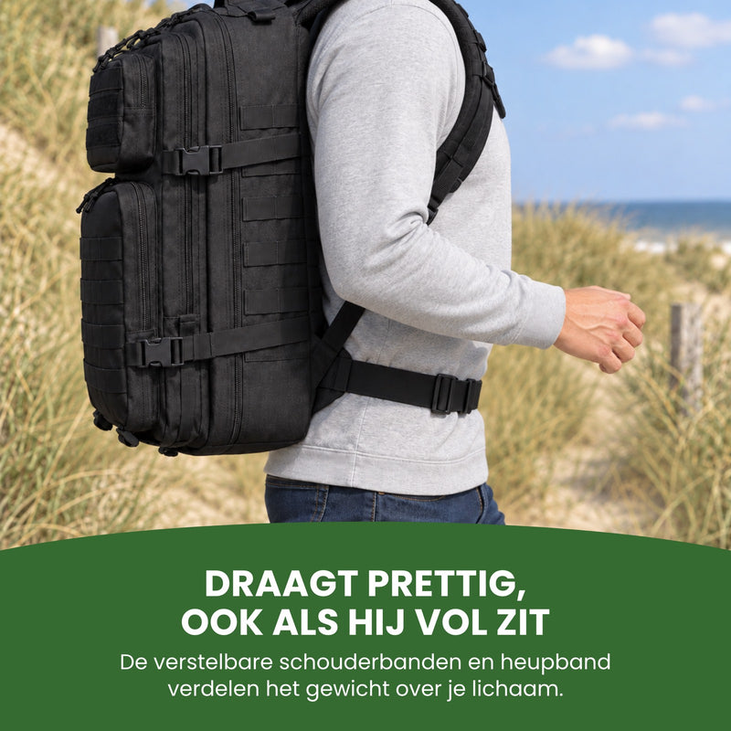 Man loopt door de duinen met de volle zwarte rugzak op zijn rug, van opzij gezien, de heupband dicht: draagt prettig, ook als hij vol zit