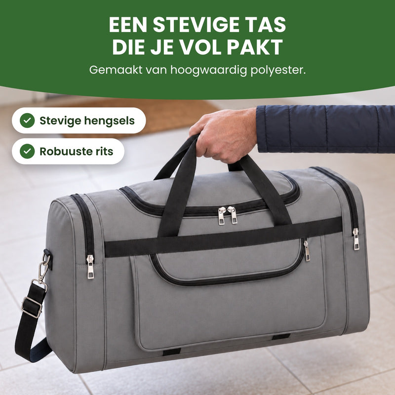 Hand tilt de volle grijze TrekMate reistas op aan de twee hengsels, van schuin boven gezien: een stevige tas die je vol pakt