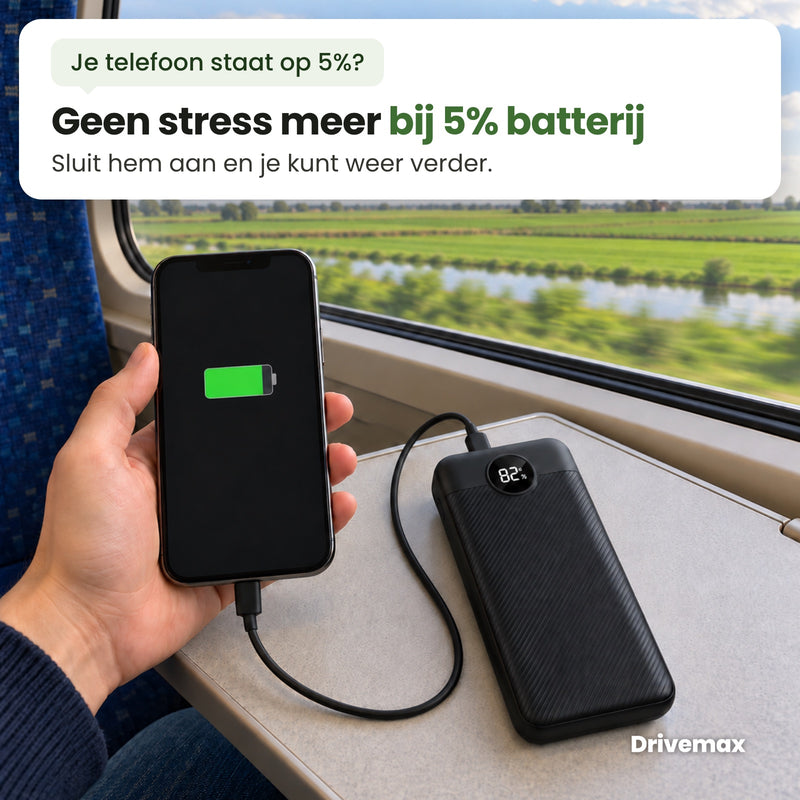 Iemand in de trein laadt zijn telefoon op met de Voltova powerbank op het tafeltje: geen stress meer bij 5% batterij