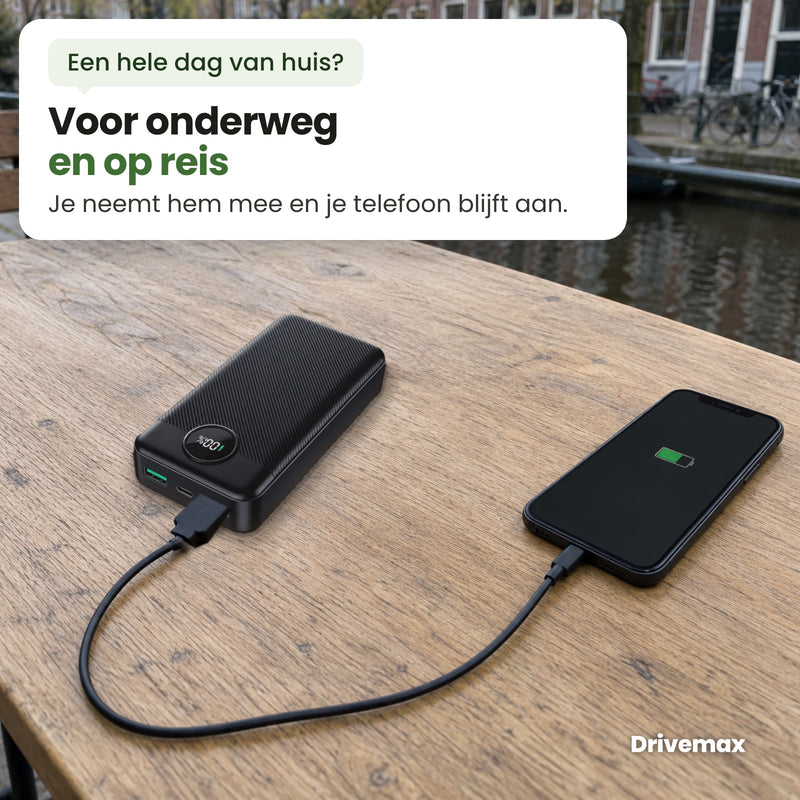 De Voltova powerbank op een houten tafel aan een Nederlandse gracht, met een kabel aangesloten op een telefoon: voor onderweg en op reis